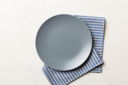 Top view on colored background empty round gray plate on tablecloth for food. Empty dish on napkin...