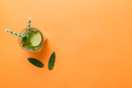 Caipirinha, Mojito cocktail, vodka or soda drink with lime, mint and straw on table background. Refreshing beverage with mint and lime in glass top view flat lay.の写真素材