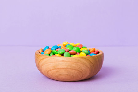 Multicolored candies in a bowl on a colored background. birthday and holiday concept. Top view with...
