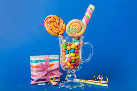 Colorful candies in cup on table on light background background. Large swirled lollipops. Creative...