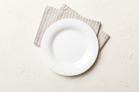 Top view on colored background empty round white plate on tablecloth for food. Empty dish on napkin with space for your design.の写真素材