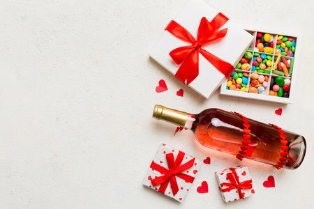 Bottle of red wine on colored background for Valentine Day with gift and chocolate. Heart shaped with gift box of chocolates top view with copy space.の写真素材