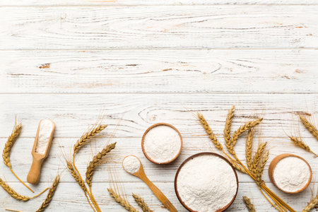 Flat lay of Wheat flour in wooden bowl with wheat spikelets on colored background. world wheat crisis.の写真素材
