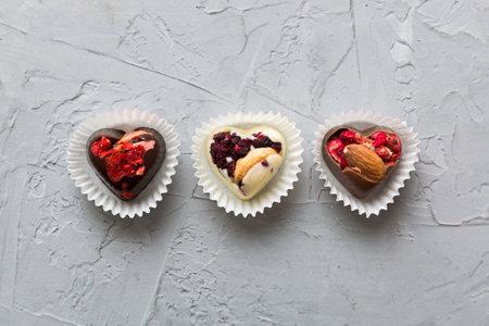 chocolate sweets in the form of a heart with fruits and nuts on a colored background. top view with...