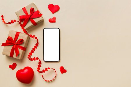 mobile phone with blank screen on colored background with hearts, valentine's day concept top view...