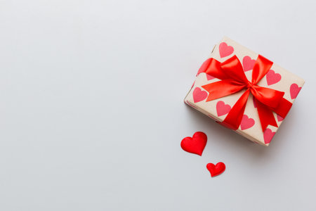Top view photo of valentine's day decorations gift box with red ribbon bow on colored background. Holiday gift boxes with top view.の写真素材