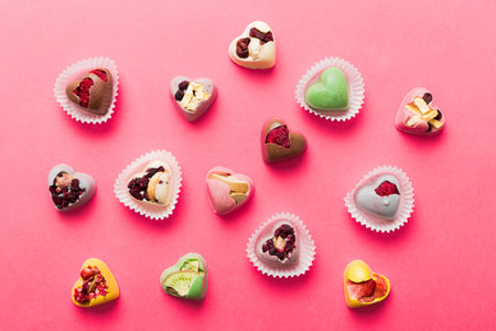 chocolate sweets in the form of a heart with fruits and nuts on a colored background. top view with space for text, holiday concept.の写真素材