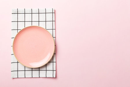 Top view on colored background empty round pink plate on tablecloth for food. Empty dish on napkin with space for your design.の写真素材