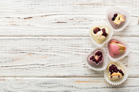 chocolate sweets in the form of a heart with fruits and nuts on a colored background. top view with...