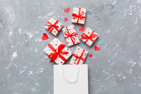 Gift boxes pop out from paper bag top view on colored background. bag packing handmade boxes fall out Concept of holidays, shopping, sale, discounts. Top view, flat lay.