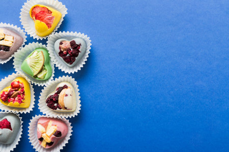 chocolate sweets in the form of a heart with fruits and nuts on a colored background. top view with space for text, holiday concept.の写真素材