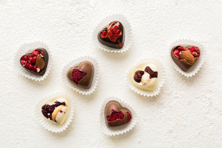 chocolate sweets in the form of a heart with fruits and nuts on a colored background. top view with...