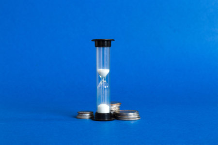Deadline and time is money concept with hourglass and US coins currency. sand clock time saving...