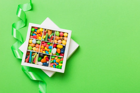 Set of different sweet candy in a paper box with a satin ribbon on a colored background. holiday concept.の写真素材