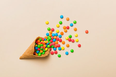 waffle cone full of assorted traditional candies falling out on colored background with copy space. Happy Holidays sale concept.の写真素材