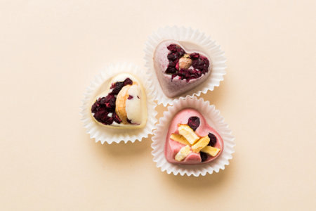 chocolate sweets in the form of a heart with fruits and nuts on a colored background. top view with...