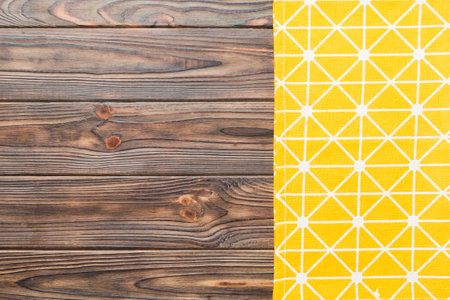 top view with yellow empty kitchen napkin isolated on table background. Folded cloth for mockup with...