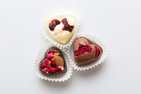 chocolate sweets in the form of a heart with fruits and nuts on a colored background. top view with...
