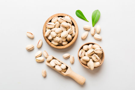 Fresh healthy Pistachios in bowl on colored table background. top view. Healthy eating concept....