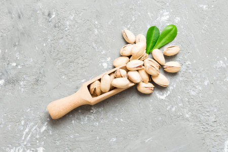 Close-up of tasty pistachio nuts in spoon with leaves on table background. top view. flat lay.の写真素材