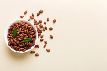 Fresh healthy peanuts in bowl on colored table background. Top view Healthy eating bertholletia...