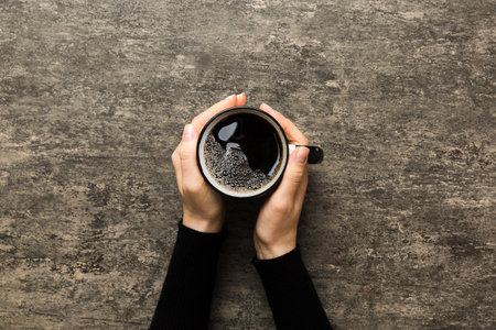 Minimalistic style woman hand holding a cup of coffee on Colored background. Flat lay, top view cappuccino cup. Empty place for text, copy space. coffee addiction. Top view, flat lay.の写真素材