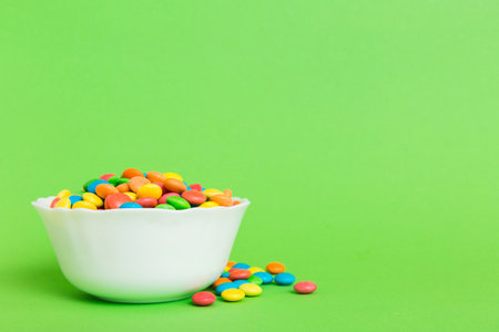 Multicolored candies in a bowl on a colored background. birthday and holiday concept. Top view with copy space.の写真素材