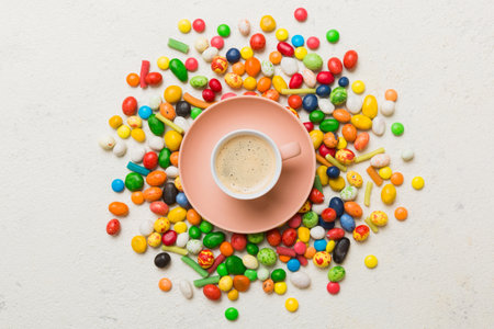 Coffee cup with chocolates and colored candy. Top view on table background with copy space.