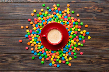 Coffee cup with chocolates and colored candy. Top view on table background with copy space.の写真素材