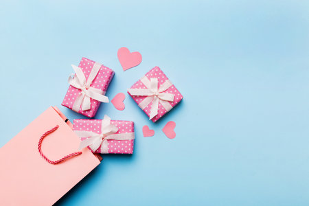 Gift boxes pop out from paper bag top view on colored background. bag packing handmade boxes fall out Concept of holidays, shopping, sale, discounts. Top view, flat lay.の写真素材