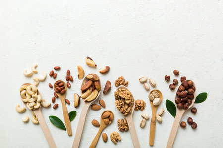 mixed nuts in white wooden spoon. Mix of various nuts on colored background. pistachios, cashews, walnuts, hazelnuts, peanuts and brazil nuts.の写真素材