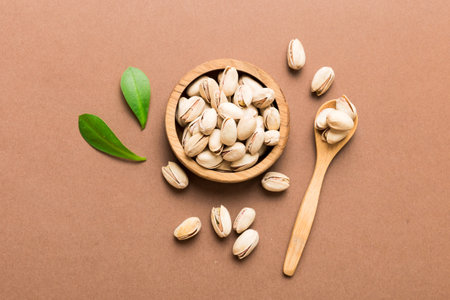 Fresh healthy Pistachios in bowl on colored table background. top view. Healthy eating concept....