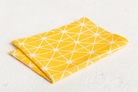 top view with yellow empty kitchen napkin isolated on table background. Folded cloth for mockup with...