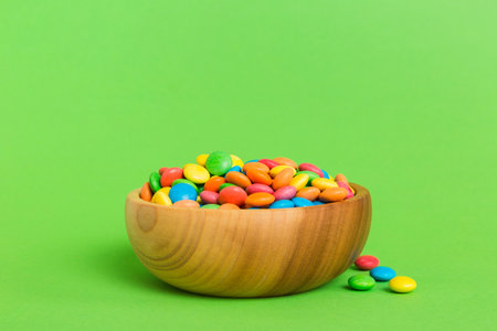 Multicolored candies in a bowl on a colored background. birthday and holiday concept. Top view with copy space.の写真素材