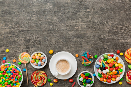 Coffee cup with chocolates and colored candy. Top view on table background with copy space.の写真素材