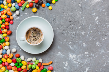 Coffee cup with chocolates and colored candy. Top view on table background with copy space.の写真素材