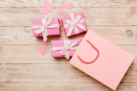 Gift boxes pop out from paper bag top view on colored background. bag packing handmade boxes fall out Concept of holidays, shopping, sale, discounts. Top view, flat lay.の写真素材