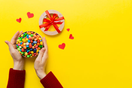 Female hands with delicious candies in box on color background.の写真素材