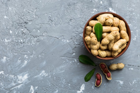 Fresh healthy peanuts in bowl on colored table background. Top view Healthy eating bertholletia...