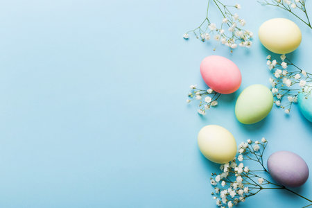 Happy Easter composition. Easter eggs on colored table with gypsophila. Natural dyed colorful eggs...