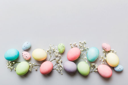 Happy Easter composition. Easter eggs on colored table with gypsophila. Natural dyed colorful eggs background top view with copy space.の写真素材