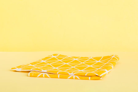 top view with yellow empty kitchen napkin isolated on table background. Folded cloth for mockup with...