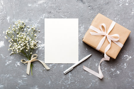 Wedding mockup with white paper list and flowers gypsophila on colored table top view flat lay. Blank greeting cards and envelopes. beautiful floral pattern. Flat lay style.の写真素材