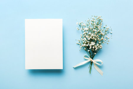 Wedding mockup with white paper list and flowers gypsophila on colored table top view flat lay. Blank greeting cards and envelopes. beautiful floral pattern. Flat lay style.の写真素材