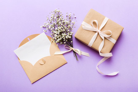 Wedding mockup with white paper list and flowers gypsophila on colored table top view flat lay....