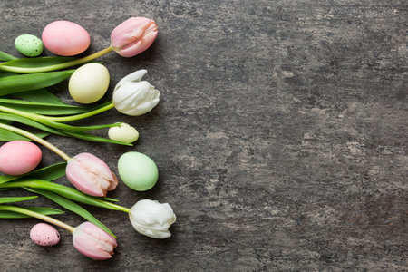 Happy Easter composition. Easter eggs on colored table with yellow Tulips. Natural dyed colorful eggs background top view with copy space.の写真素材