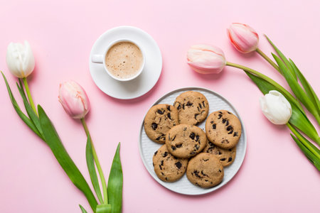Cup of coffee mug with coffee, cookies and tulips on a colored background. Greeting spring card top view.の写真素材