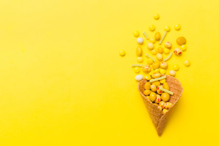 waffle cone full of assorted traditional candies falling out on colored background with copy space. Happy Holidays sale concept.の写真素材