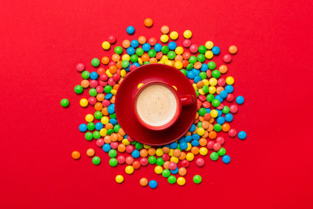 Coffee cup with chocolates and colored candy. Top view on table background with copy space.の写真素材