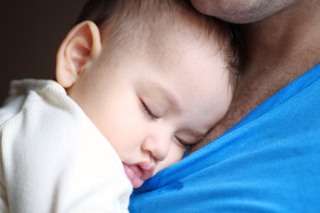Cute newborn baby sleeping in father arms close up. A loving father carries her newborn baby at home. portrait of a happy mother holding a sleeping baby.の写真素材